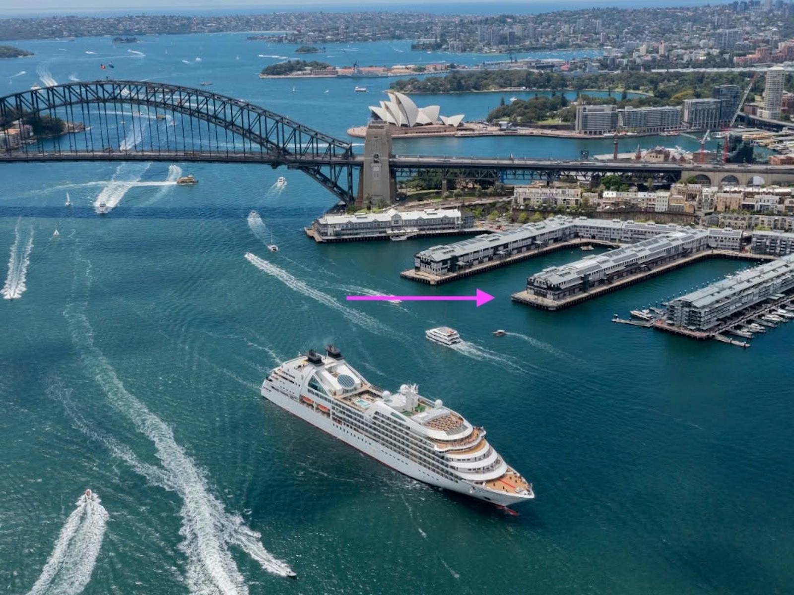 Aerial photograph of the Sydney Harbour with the finger wharfs showing and an arrow venue