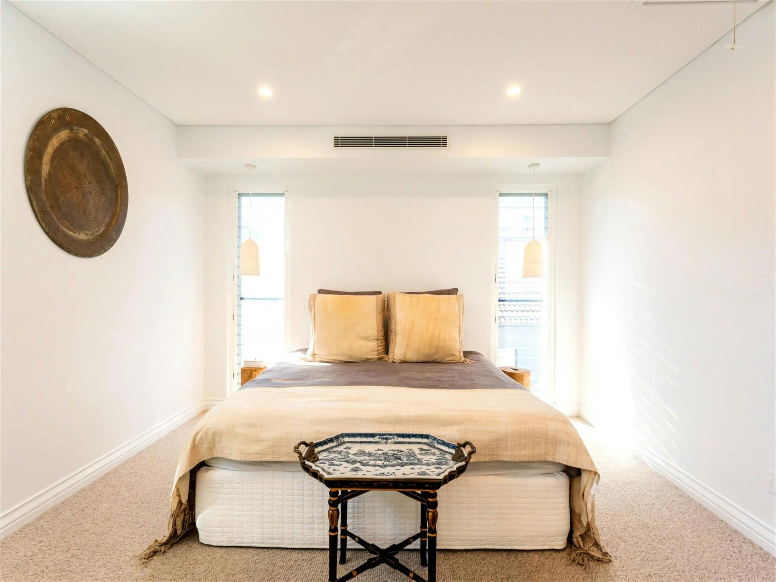 das Hauptschlafzimmer mit seinen ruhigen Farbpaletten und mehreren Fenstern