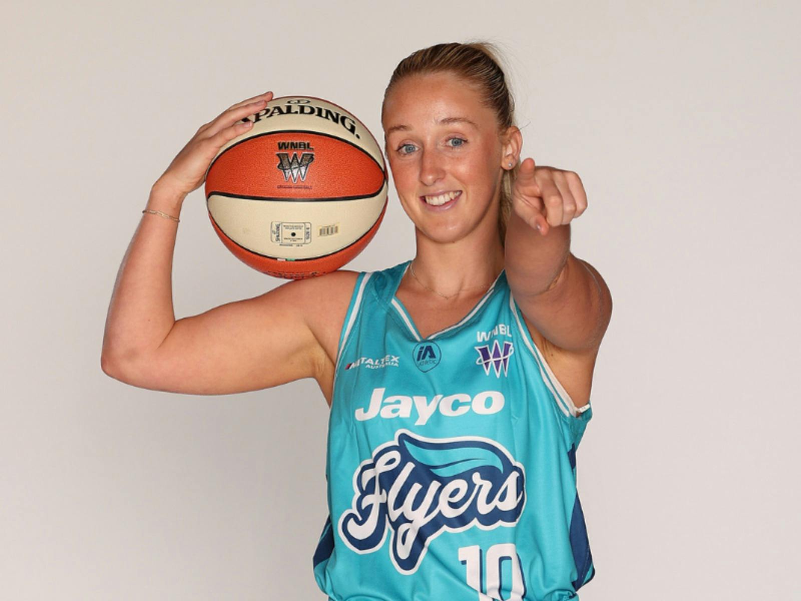 Haylee Andrews in Her Flyers uniform holding a basketball and pointing