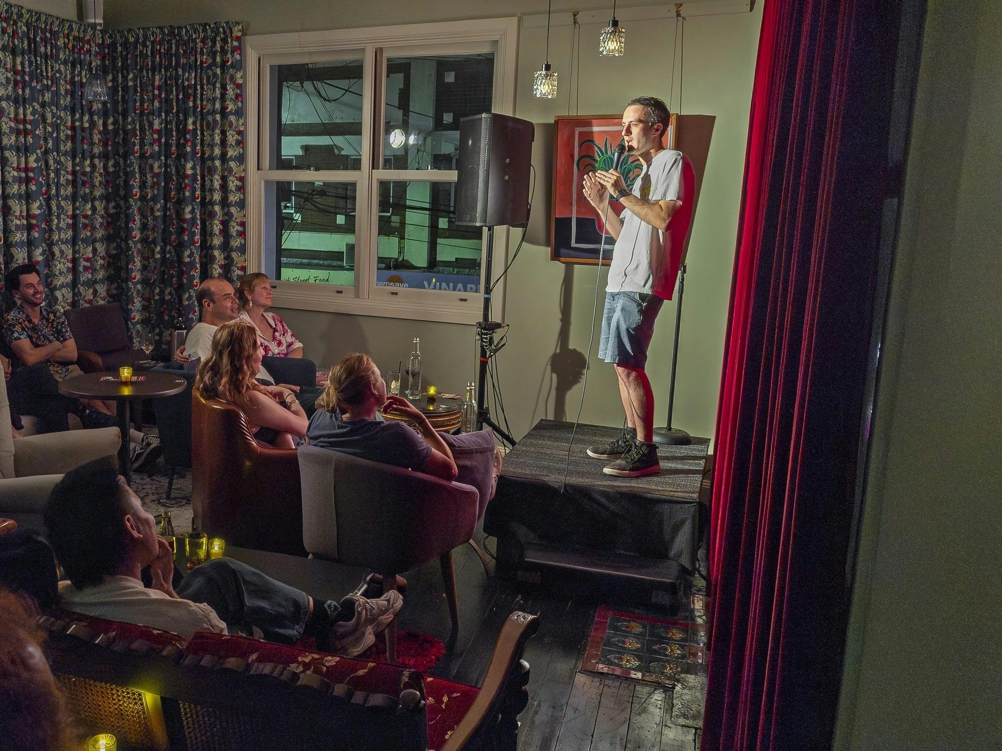 Audience enjoying a stand-up comedy show in the cosy upstairs lounge at We Three bar