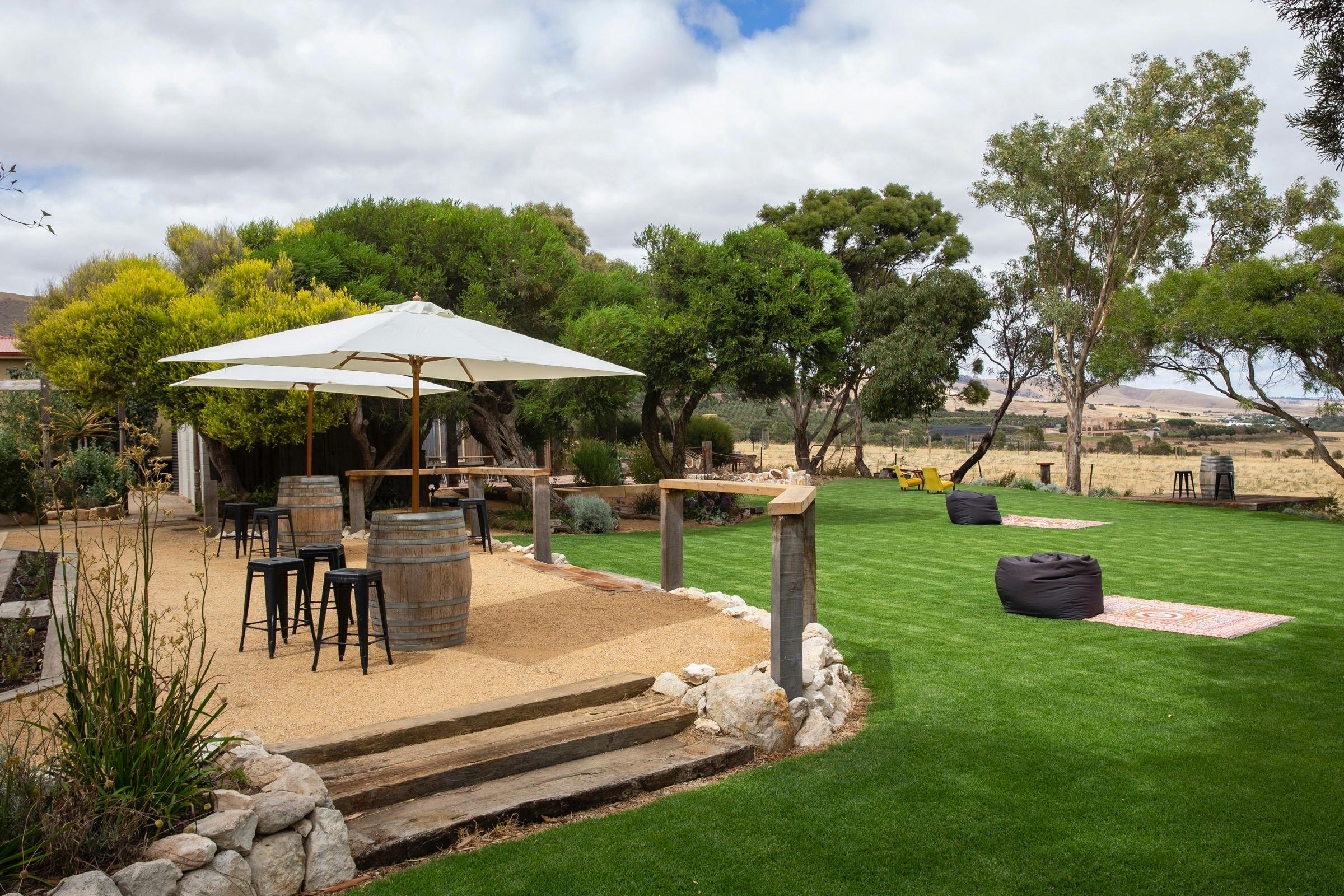 The garden area at Berg Herring  wines, with grass & wine barrel tables