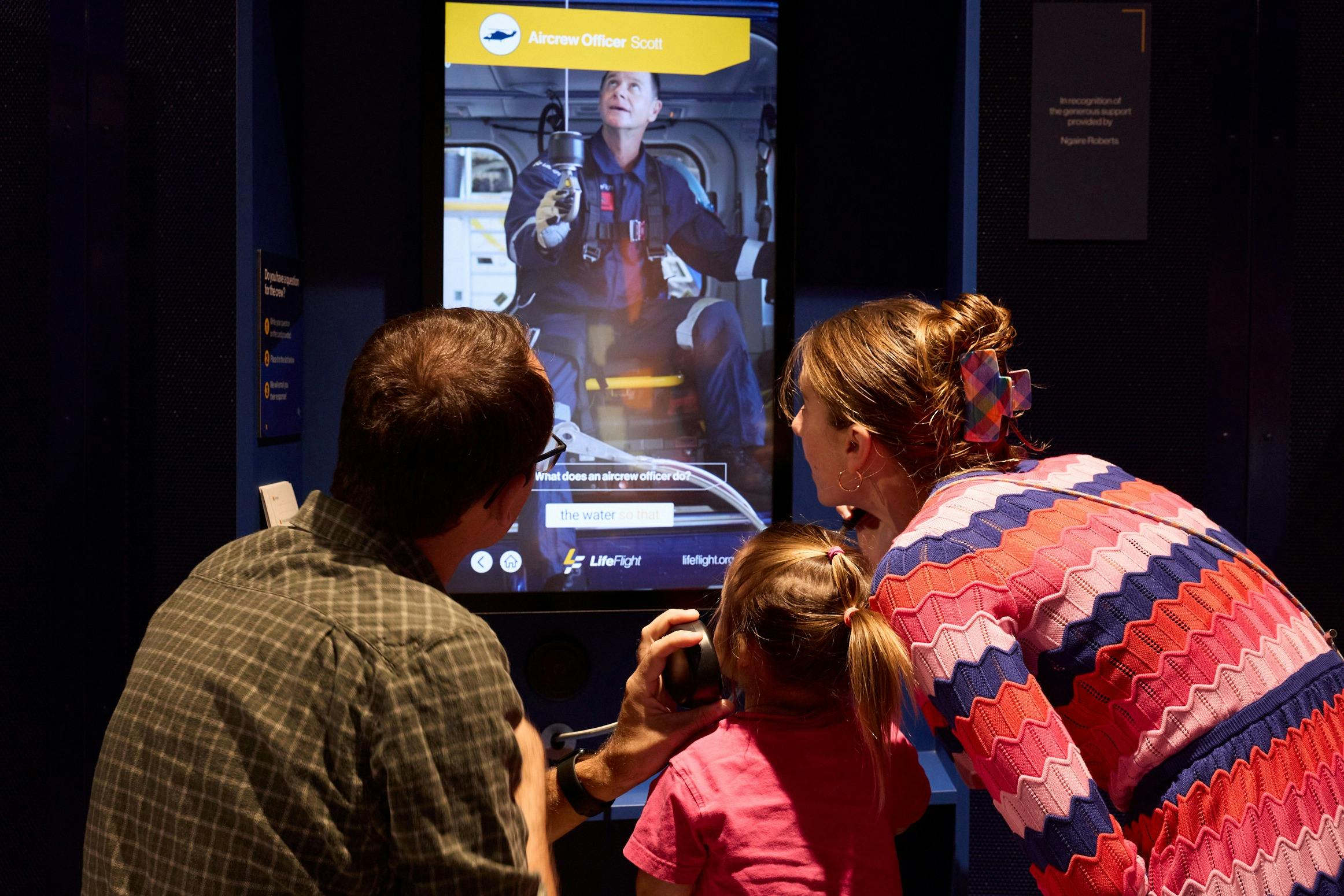 Family watching digital interactive screen at visitor centre