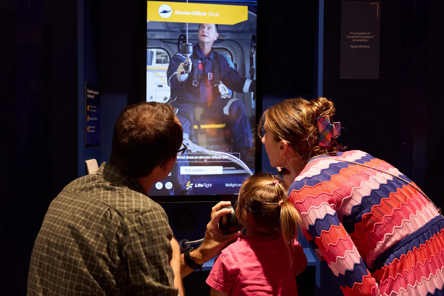 Family watching digital interactive screen at visitor centre