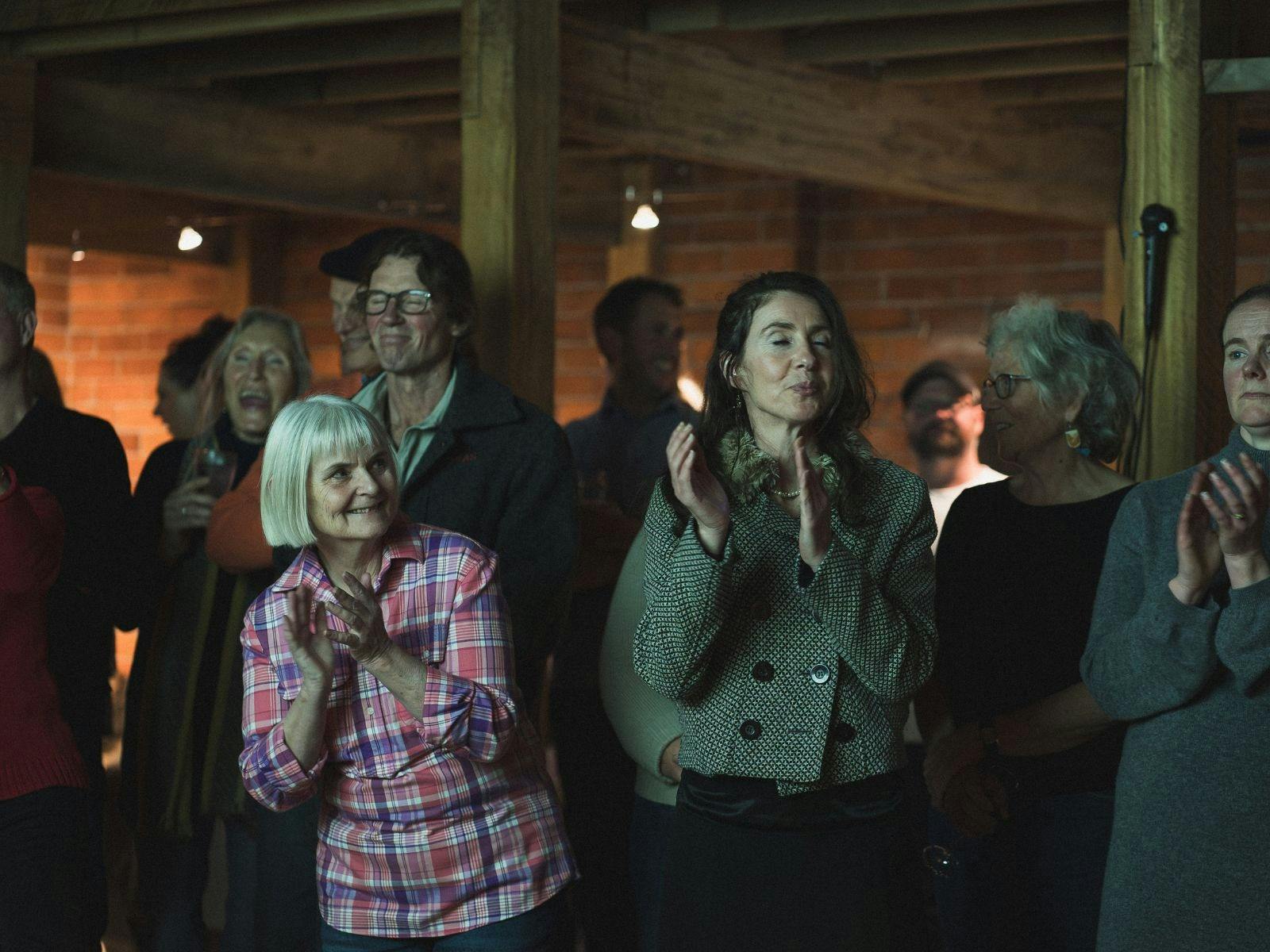Several people at Shed Choir in The Don clapping and laughing during a song break.