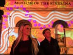 Couple admiring colourful light projections on the Museum of the Riverina.