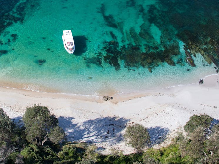 Boat in clear water close to white sandy shore