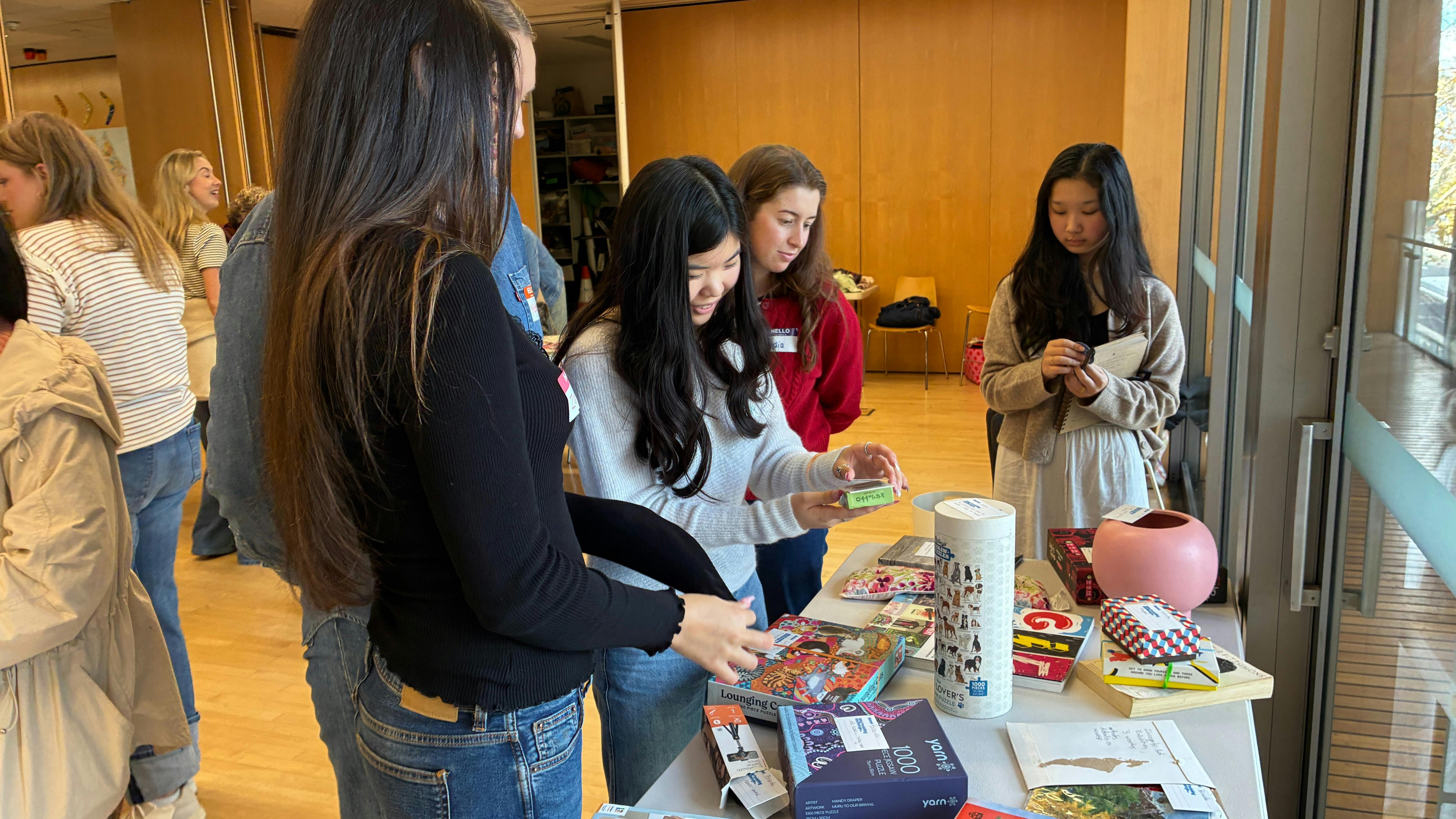 A group of 5 teenagers looking at a table of donated items