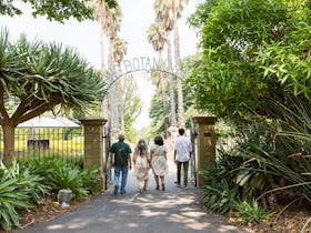 Four people with backs towards the camera walking under the entry gate to the garden