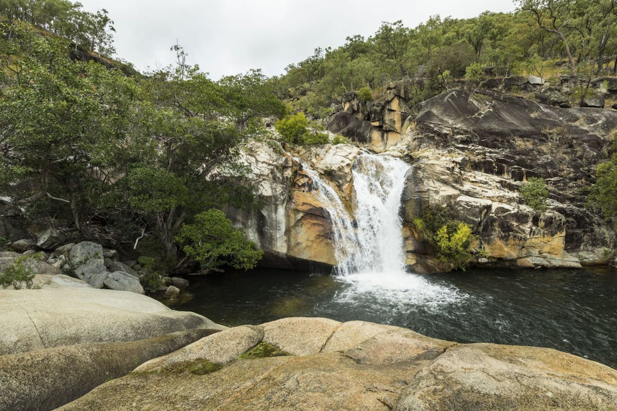 Water cascading over granite boulders into a natural pool.