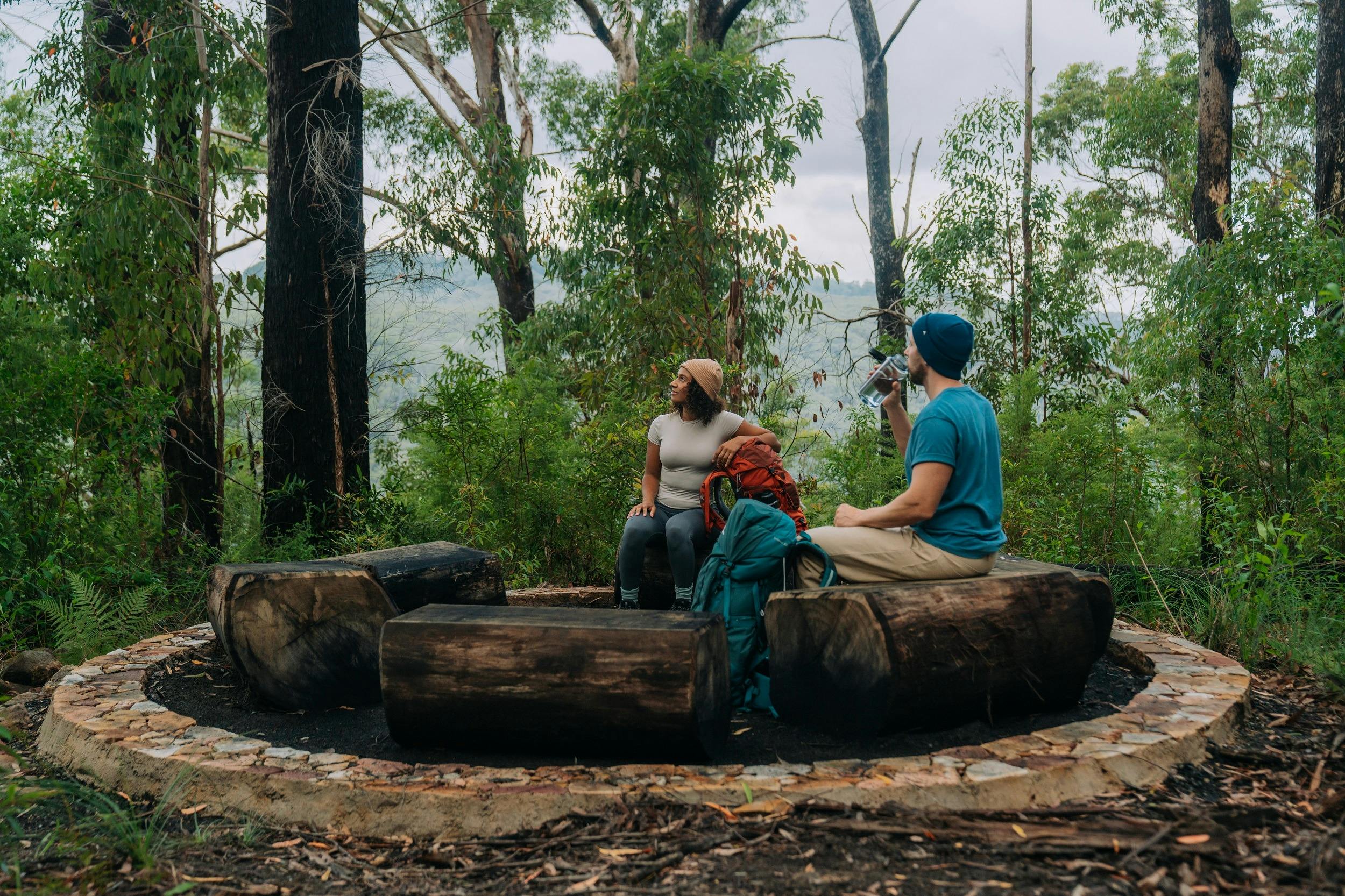 Two hikers sit in a yarning circle at Weeun Weeun campground on Gidjuum Gulganyi Walk.