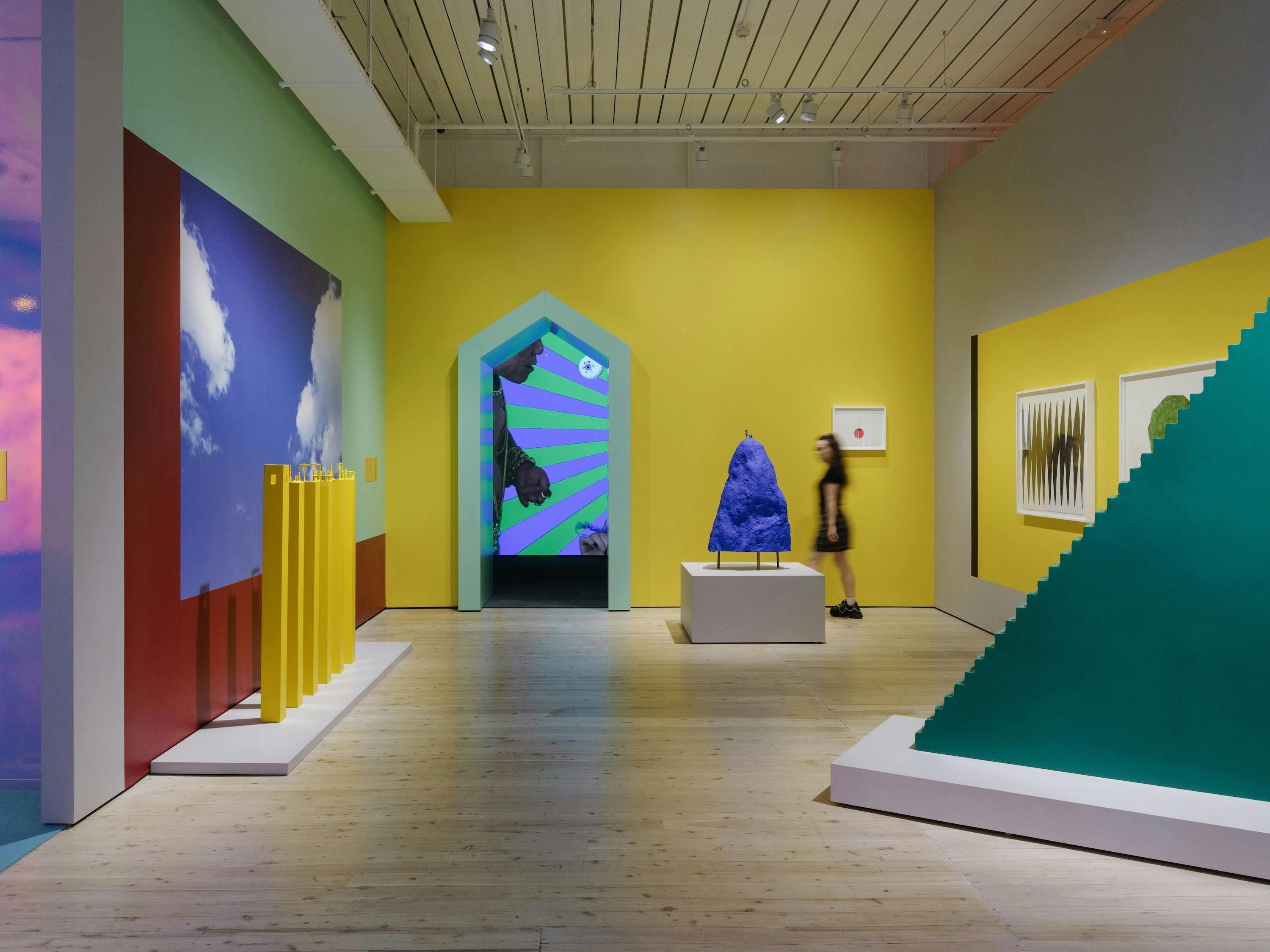 Gallery room with yellow walls and colourful sculptures
