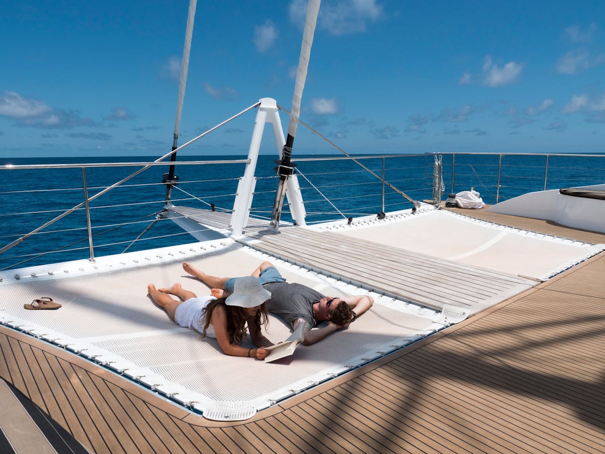 Sunbathers relax with a book on the boom nets on the front of Passions of Paradise