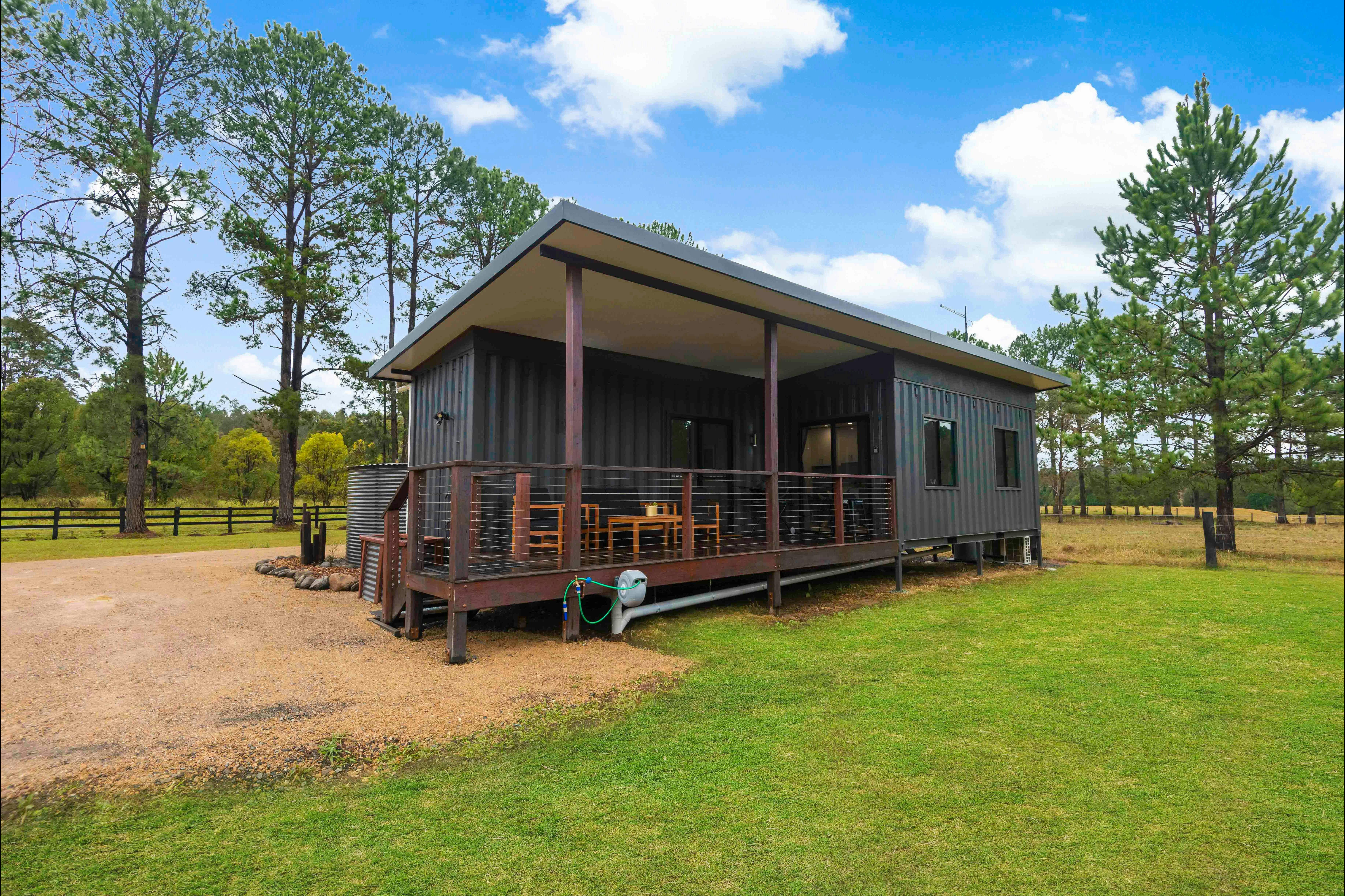 External shot of Nightcap Cottage showing entry, hardwood deck, outdoor furniture and general style