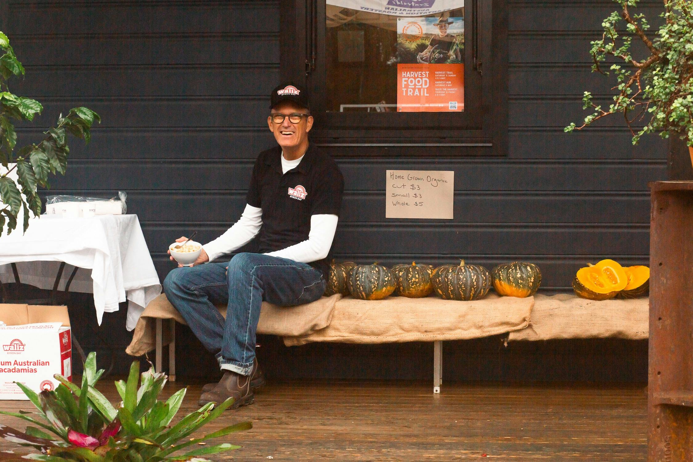Man sitting on bench with row of pumpkins
