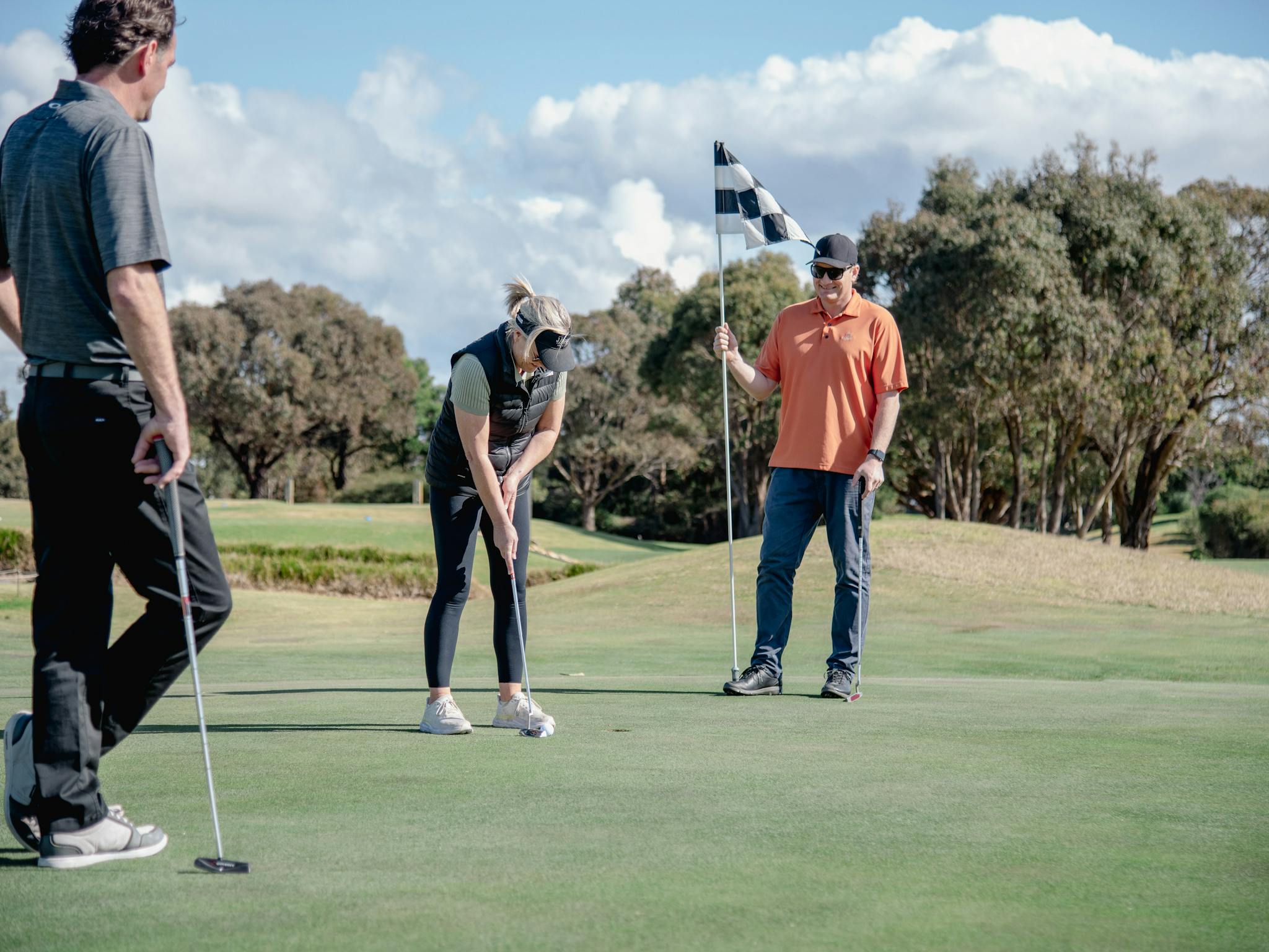 Lady putting ball while playing golf with friends at Metung Golf Club