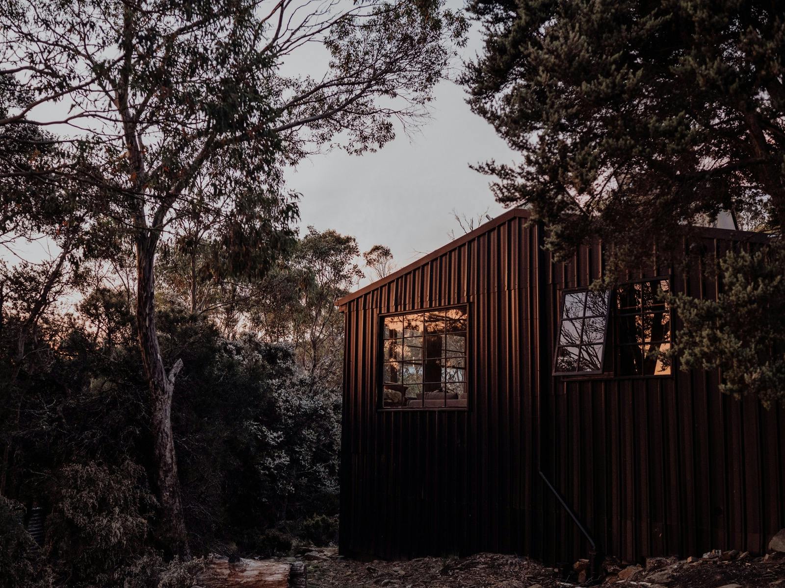 The exterior of Camp Nowhere is black, sleek but somehow blends in to the surrounding bush.