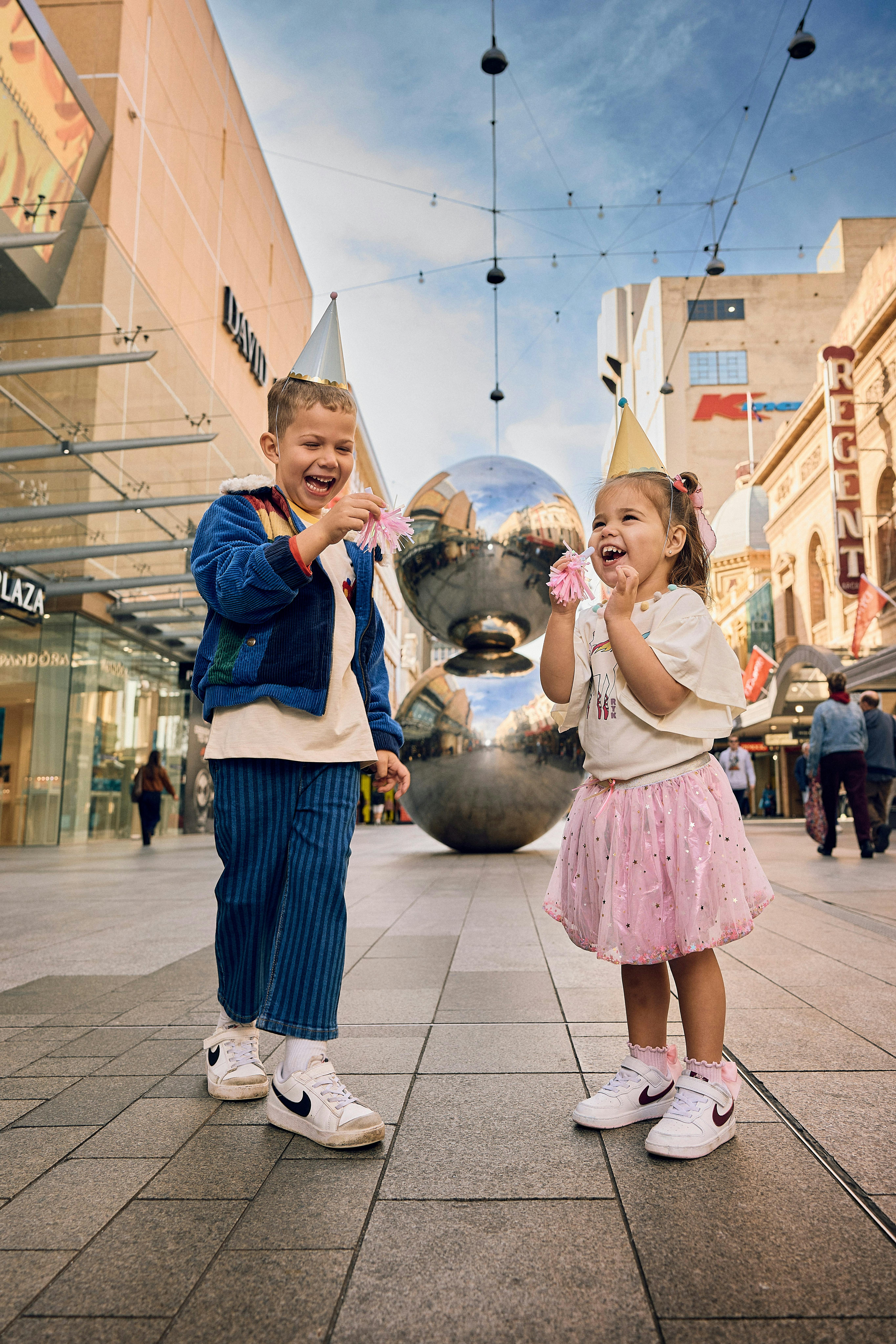 Kids laughing in front of Malls Balls with party hats