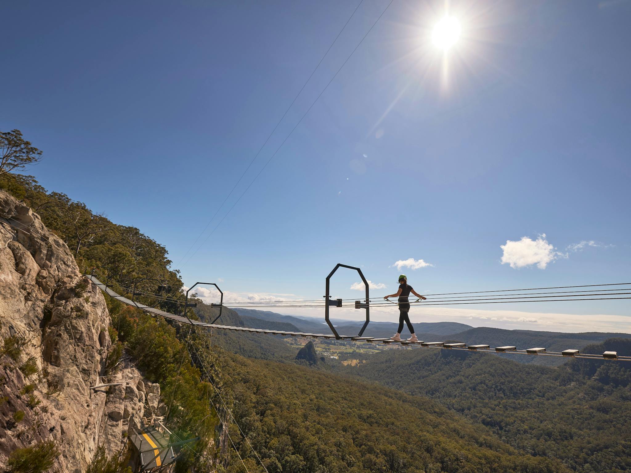 Woman walking across Via Ferrata at Happitat Adventure Park Woman walking across Via Ferrata at Happitat Adventure Park