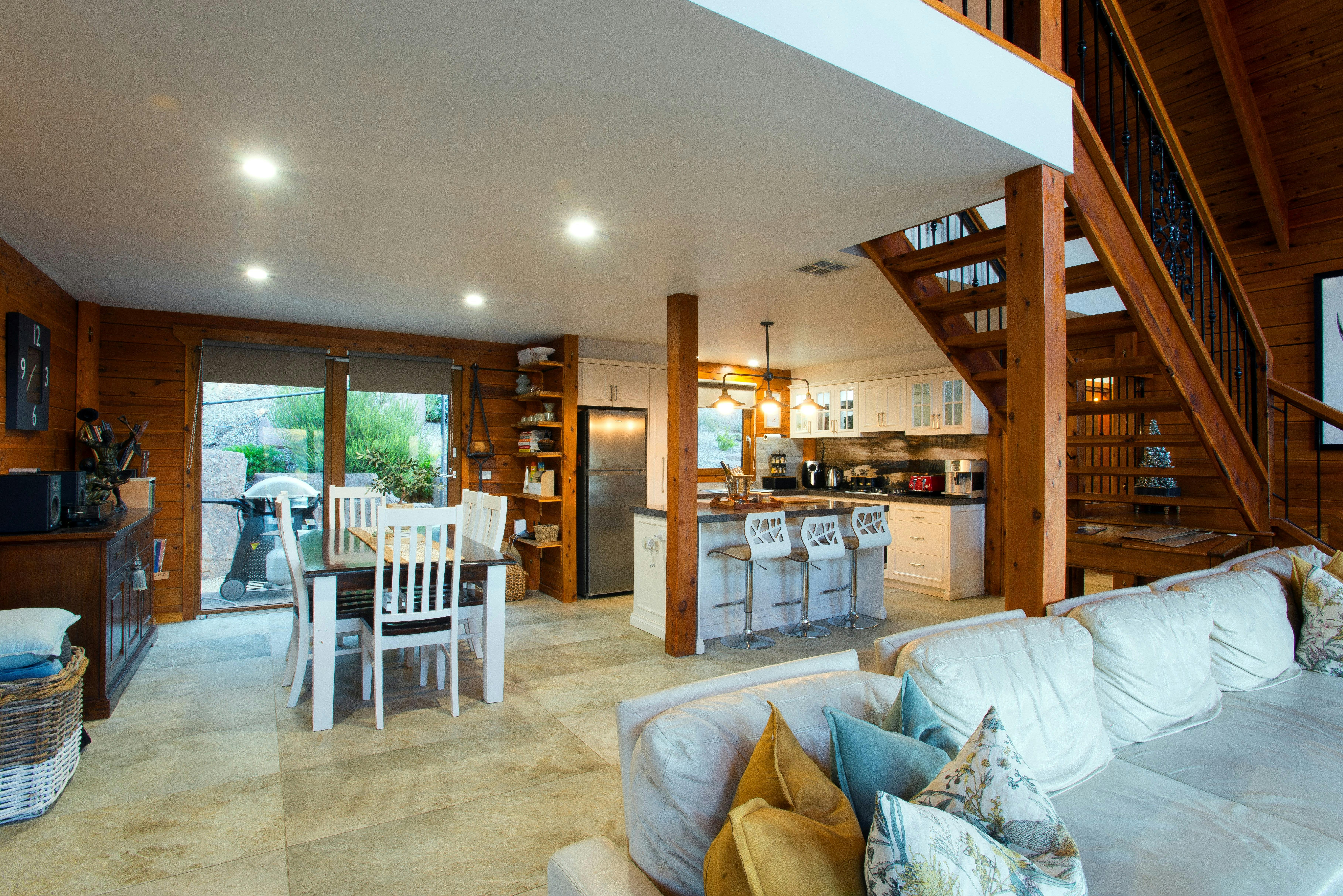Kitchen and living room in open-plan layout with wooden stairs to main bedroom
