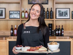 lady holds a cheese platter and smiles at camera