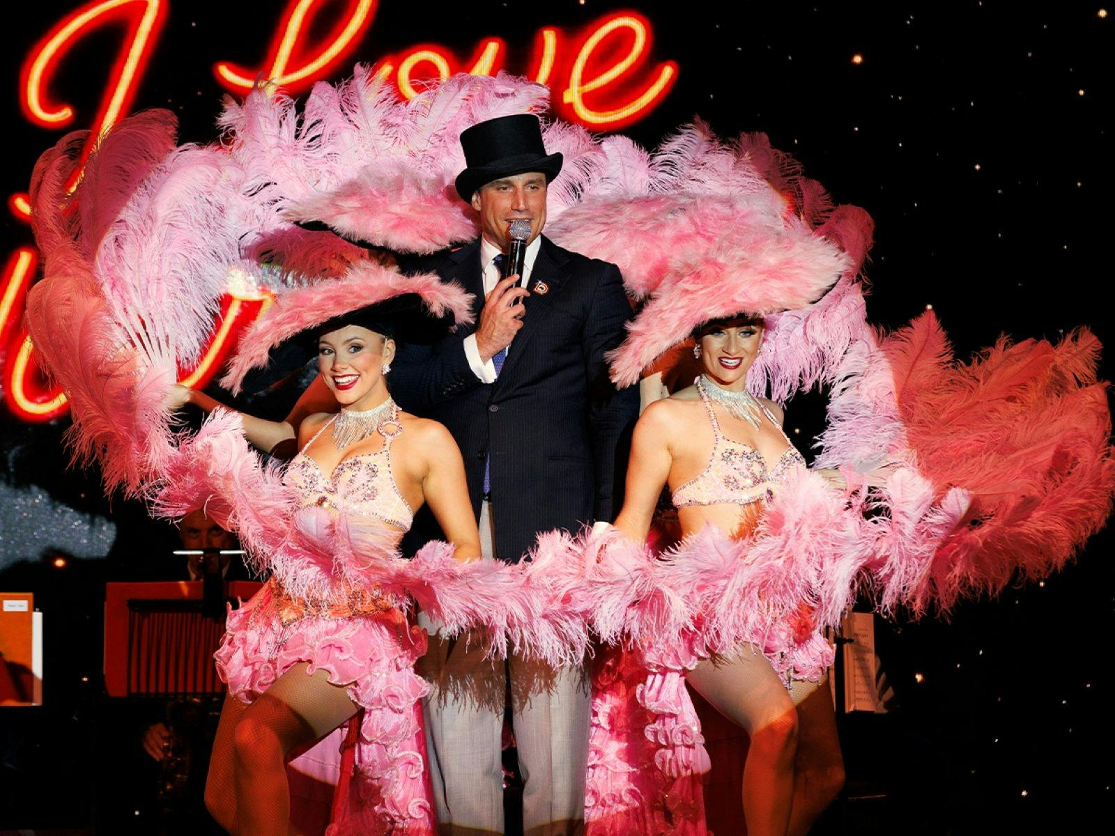 A man standing inbetween two cabaret dancers