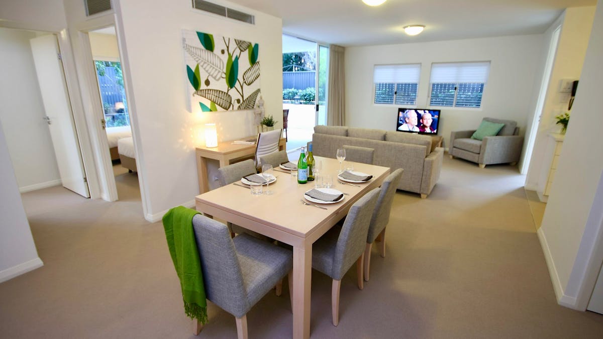 Spacious open-plan living and dining area with six-seat dining table, lounge, flat-screen television