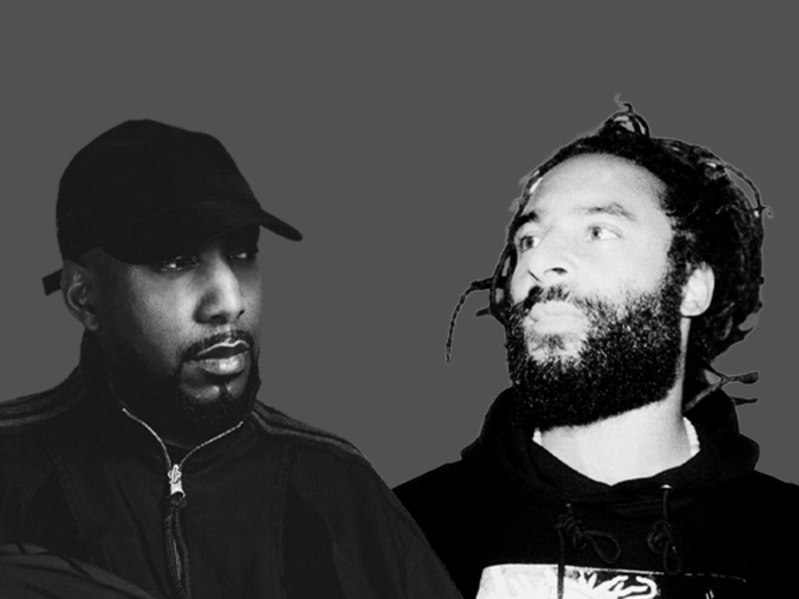 Black-and-white image of two bearded men, one wearing a cap, facing each other