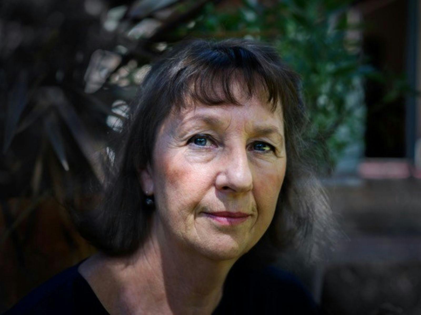A close up image of a woman with long dark hair and a fringe