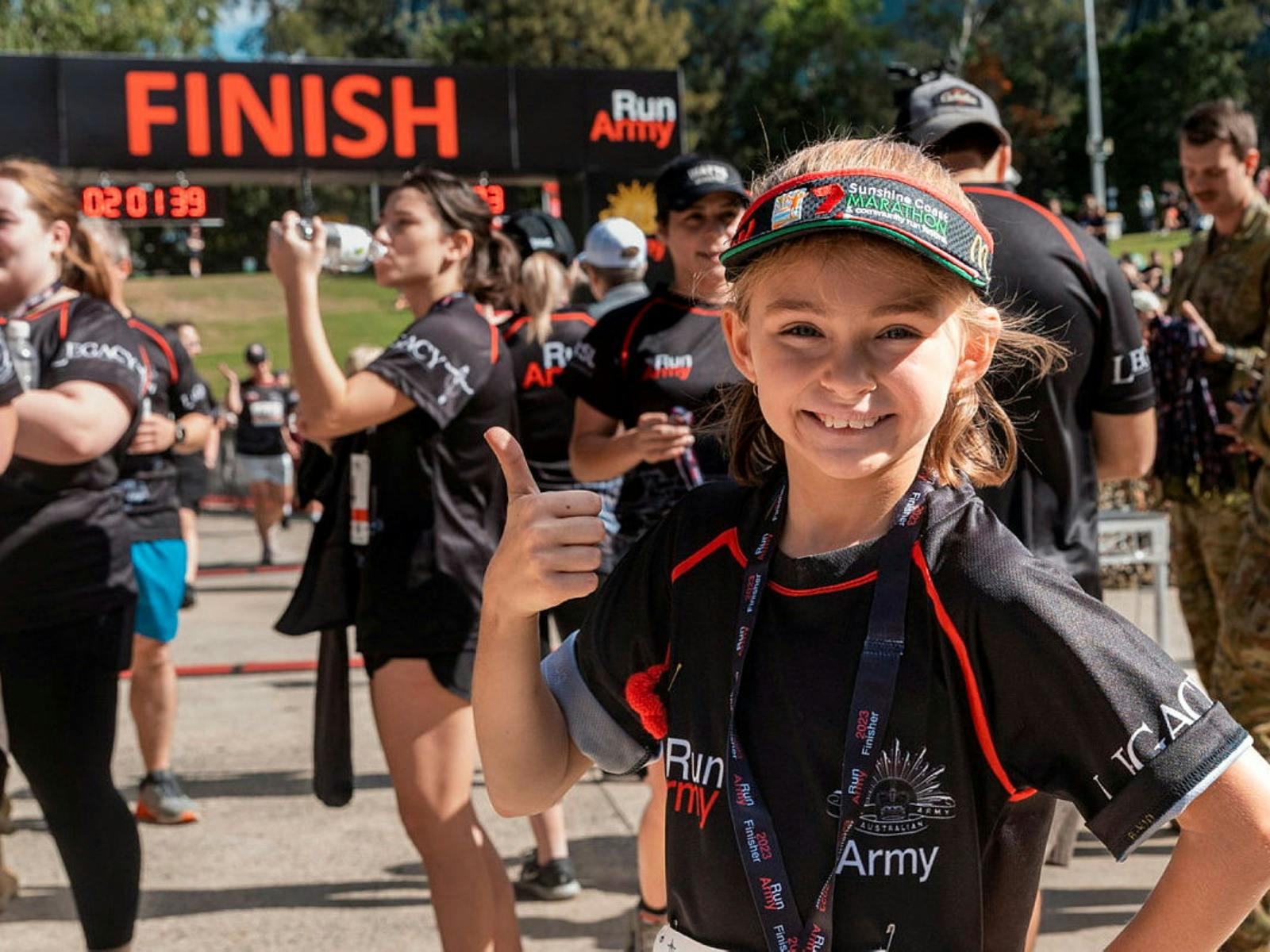 Girl giving a thumbs up at the finish line