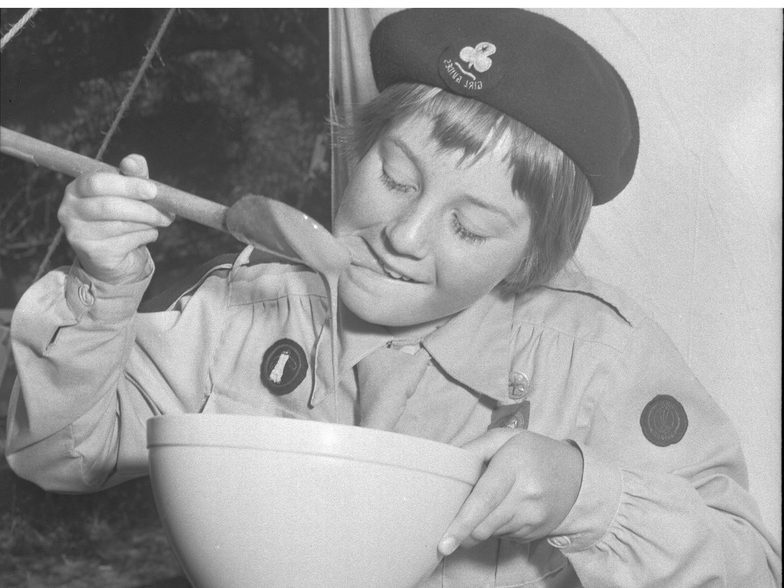 Girl Guide Eleanor Jaeger samples the custard at Guide Camp, 1960.