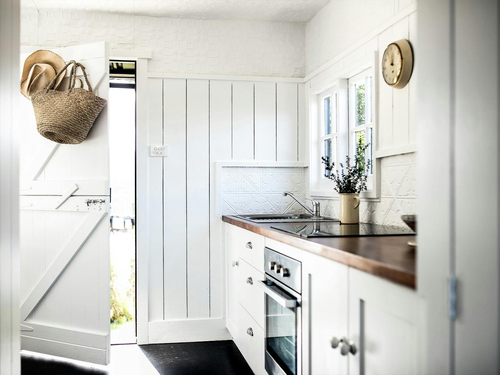 A white country style kitchen with a wooden benchtop
