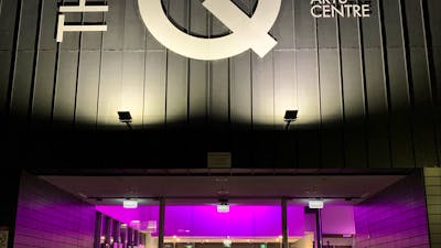 Façade of building with large white lettering and internally lit with purple lights