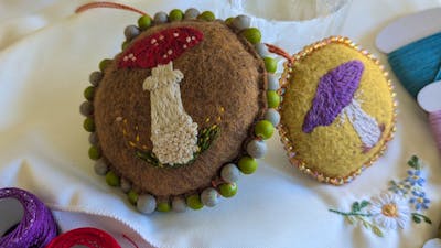Fabric decorative hangers embroidered with mushrooms next to a gin and tonic
