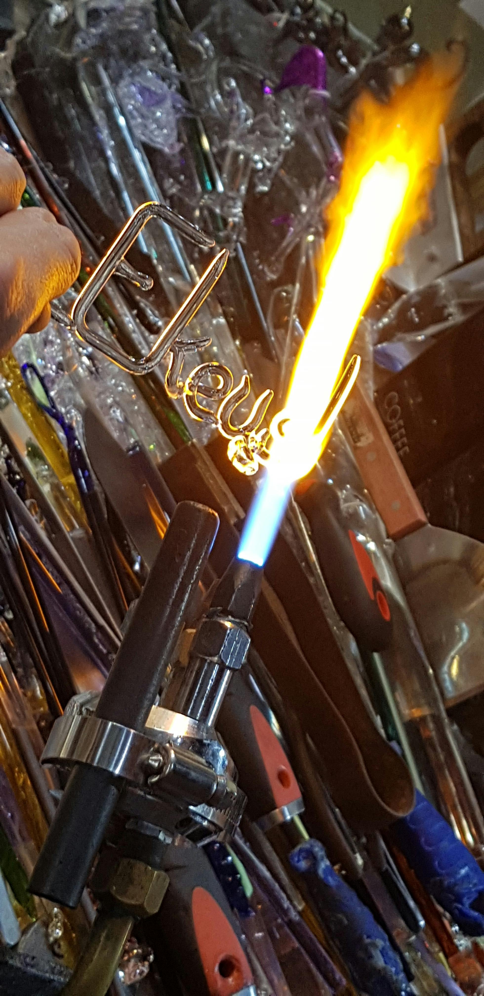 A customer watches in excitement as her name gets made from molten glass