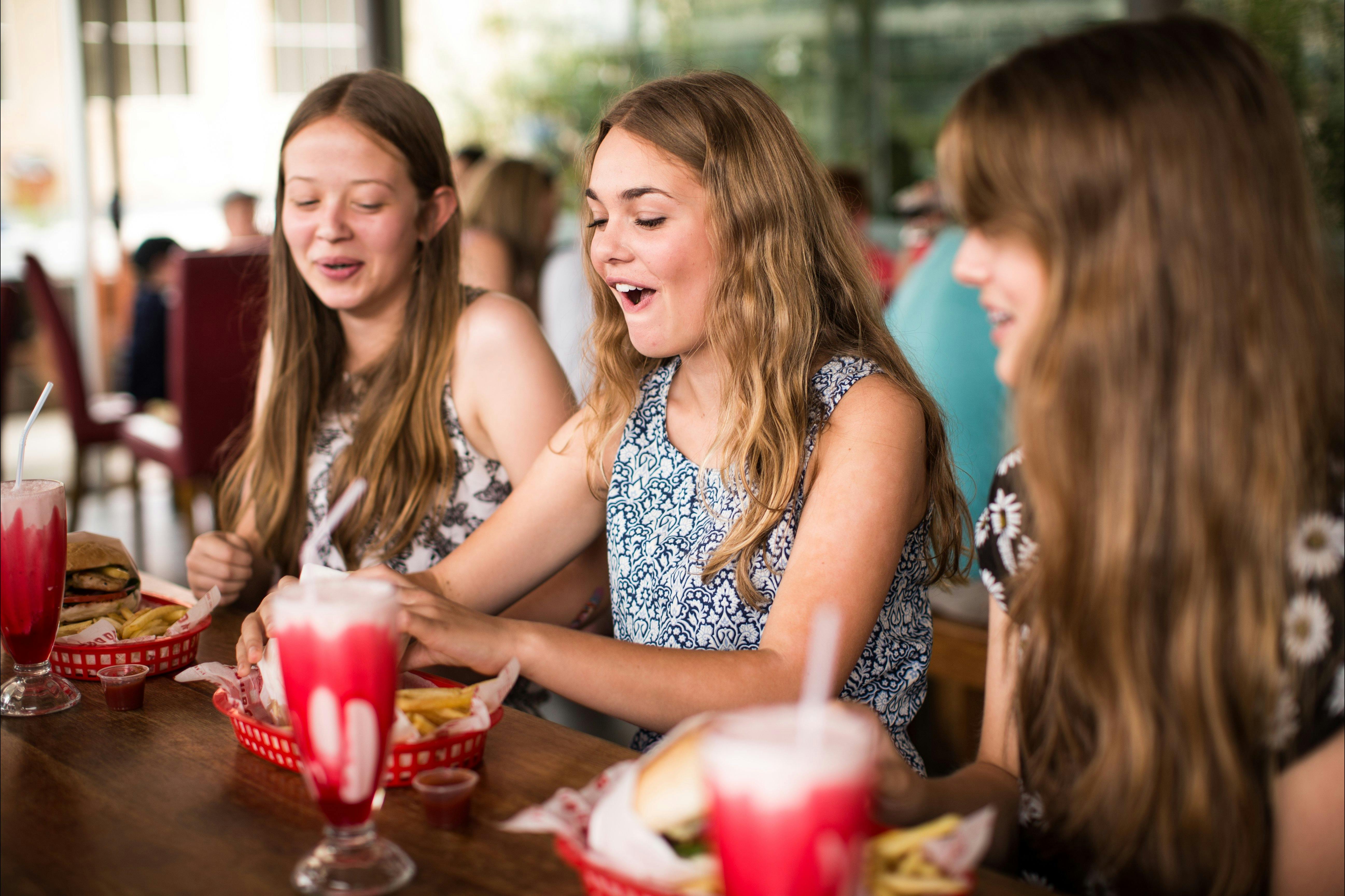 Three teenagers sitting down to their burgers