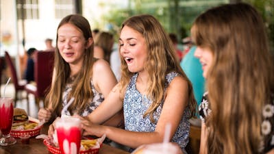 Three teenagers sitting down to their burgers