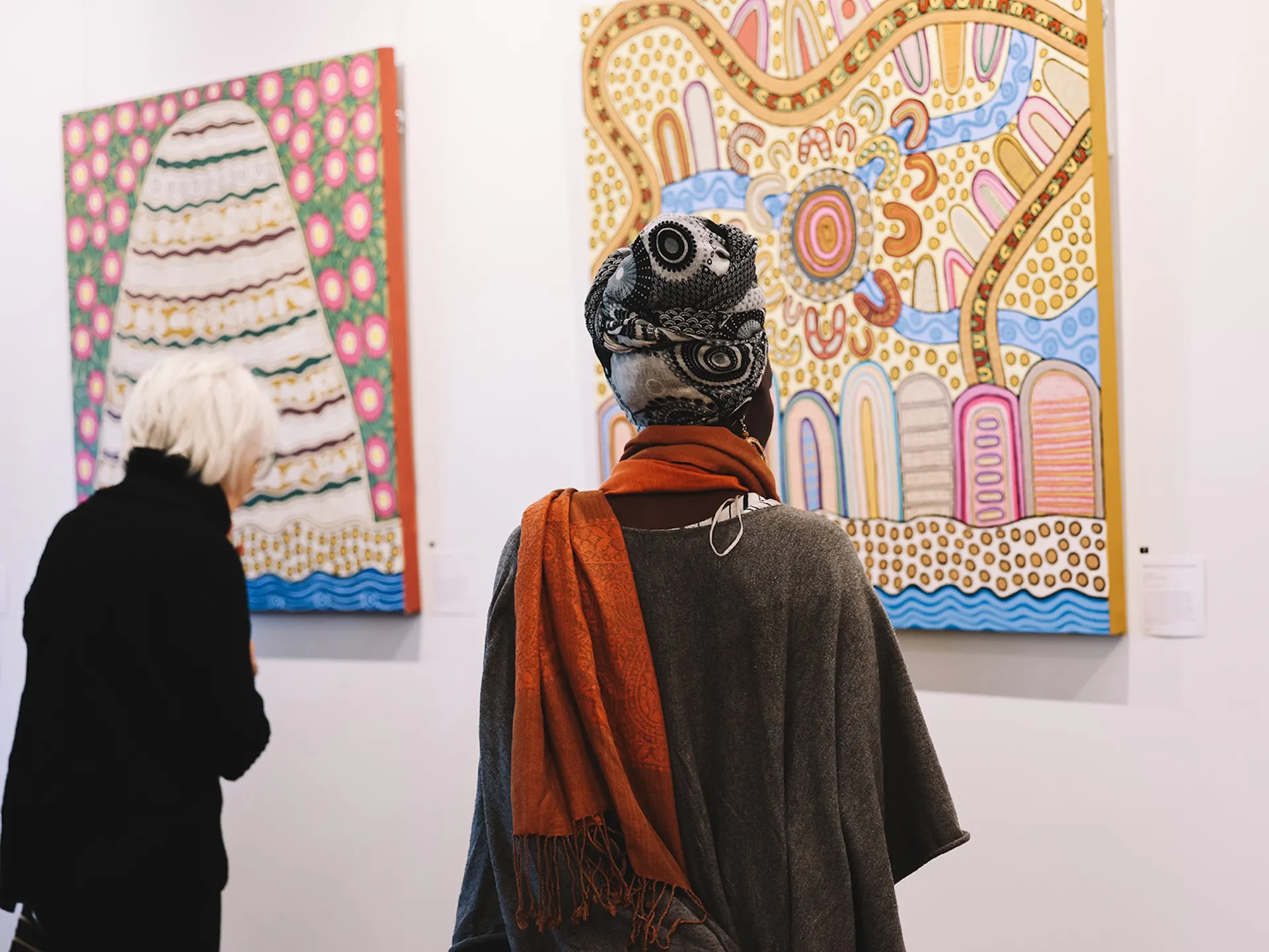 Audience looking at paintings of middens 2 women one with a head scarf