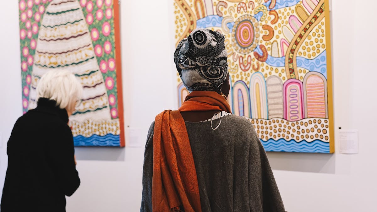 Audience looking at paintings of middens 2 women one with a head scarf Audience looking at paintings of middens 2 women one with a head scarf