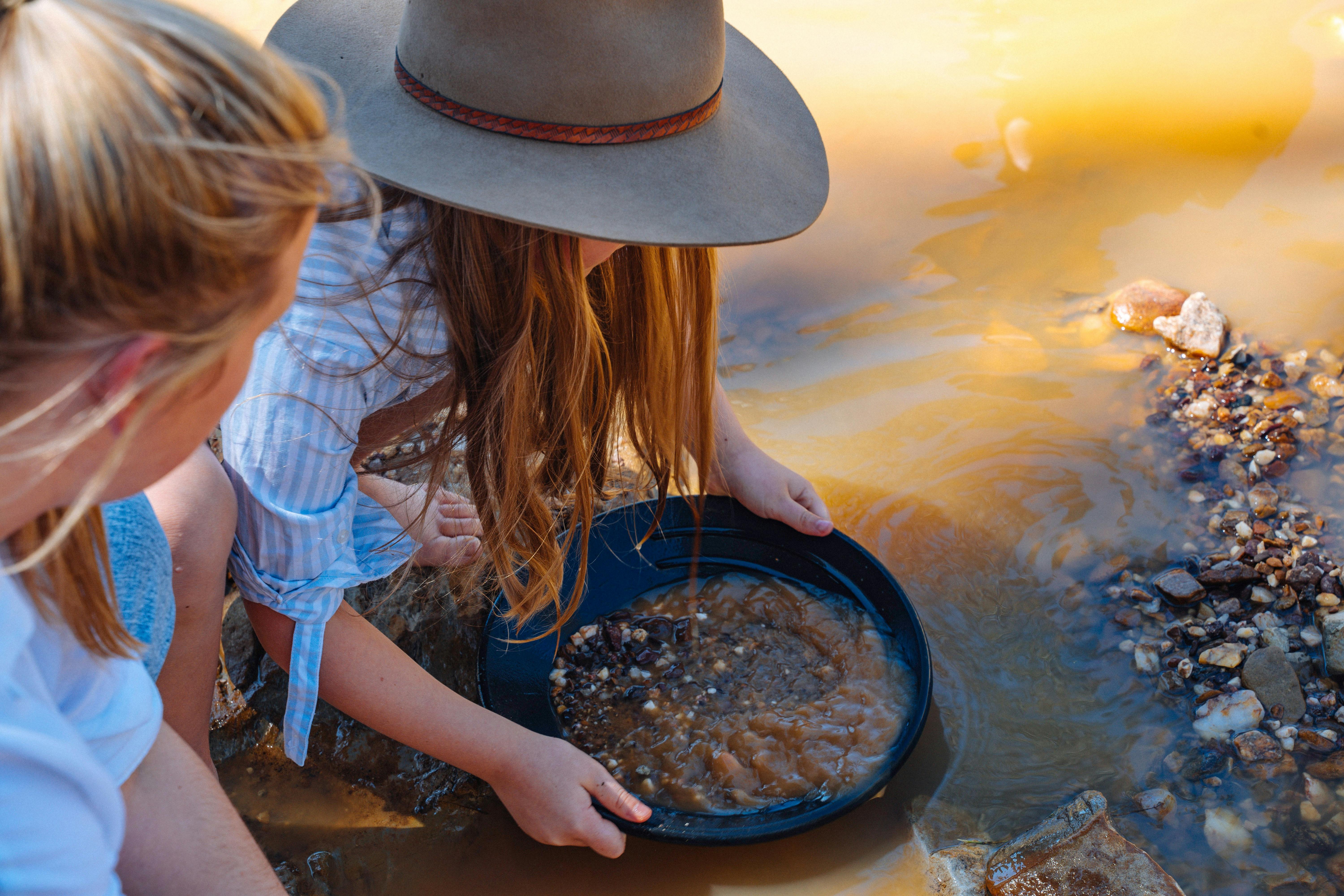 Girl panning out dirt to find gold.