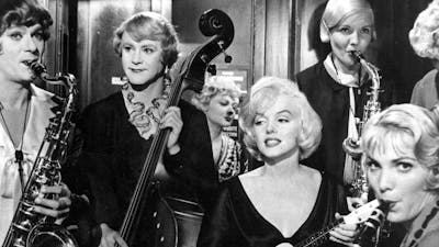 Black and white still of Marilyn Monroe surrounded by musicians