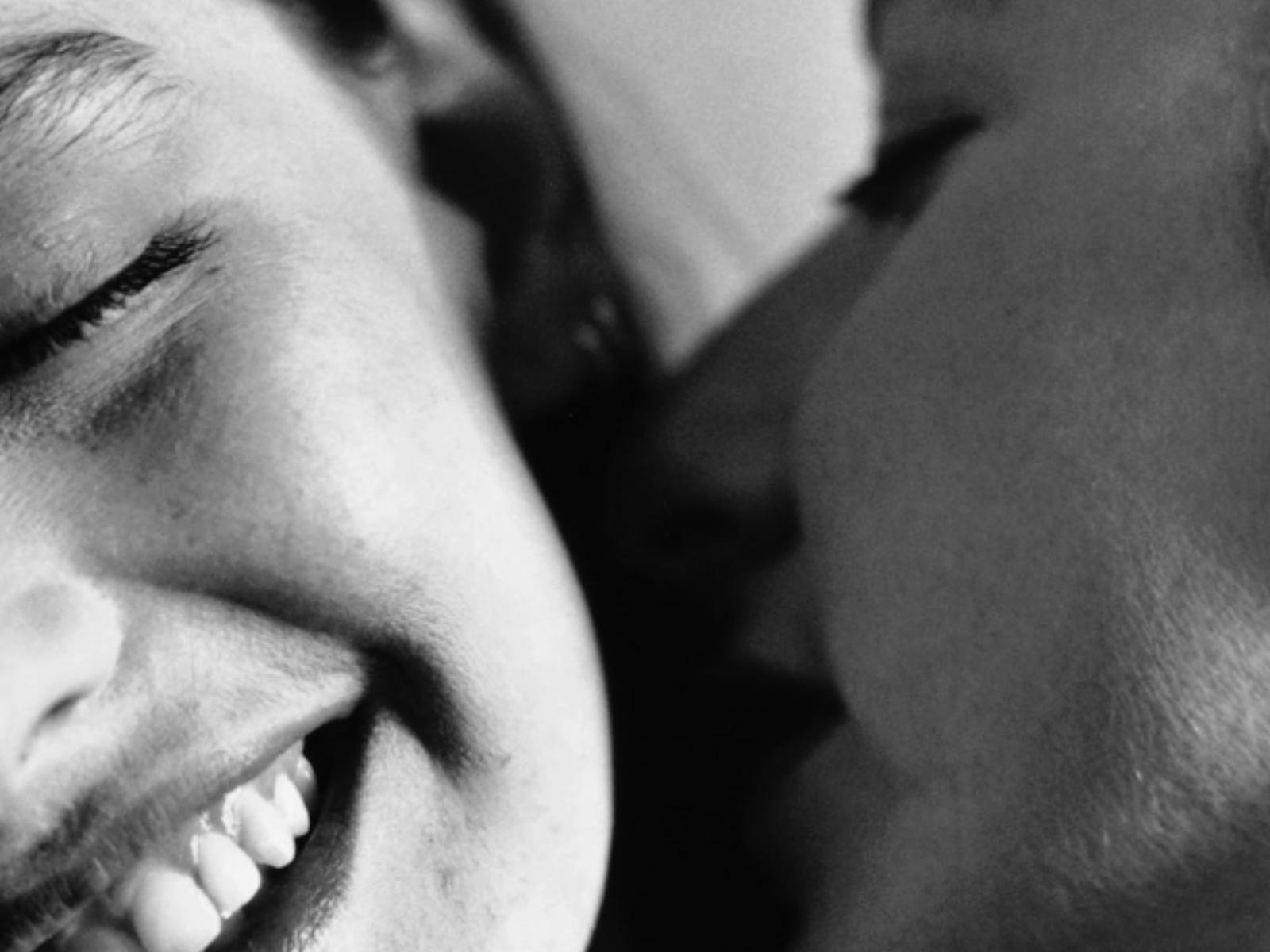 Black-and-white scene of a woman kissing another woman on the cheek.