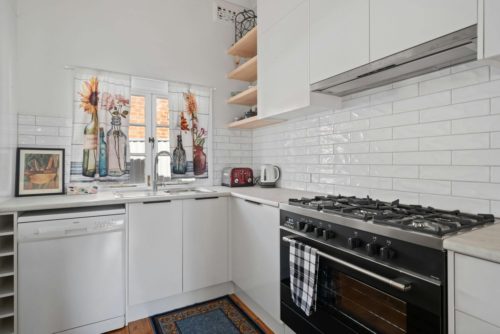 最新の家電製品とカーテン付きの窓を備えたモダンな白いキッチン。