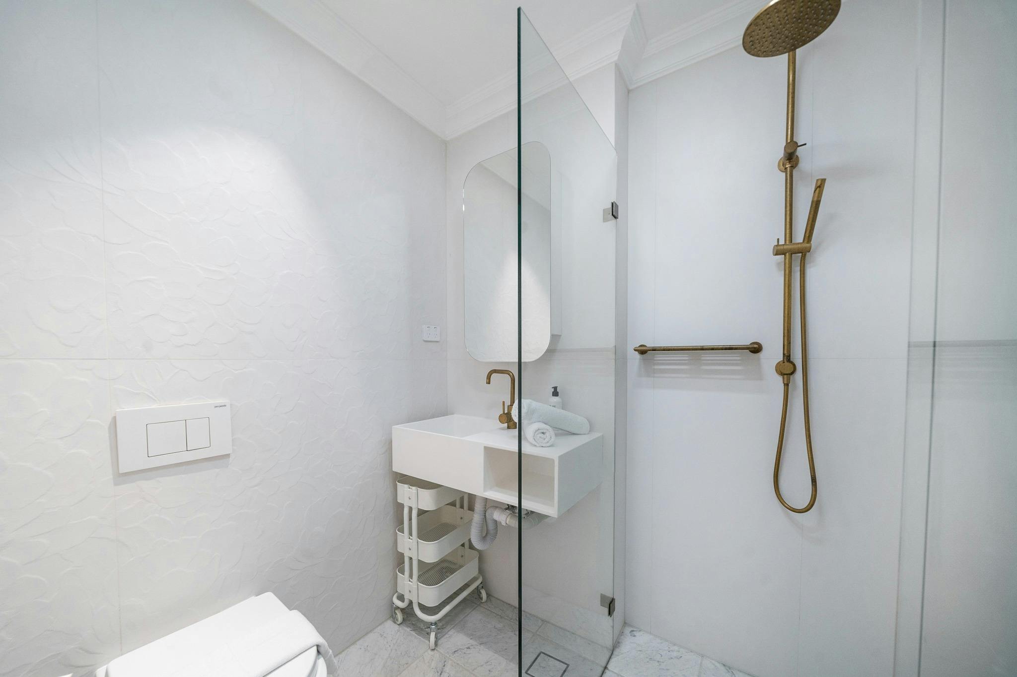 Shower area with a sleek design and golden fixtures.