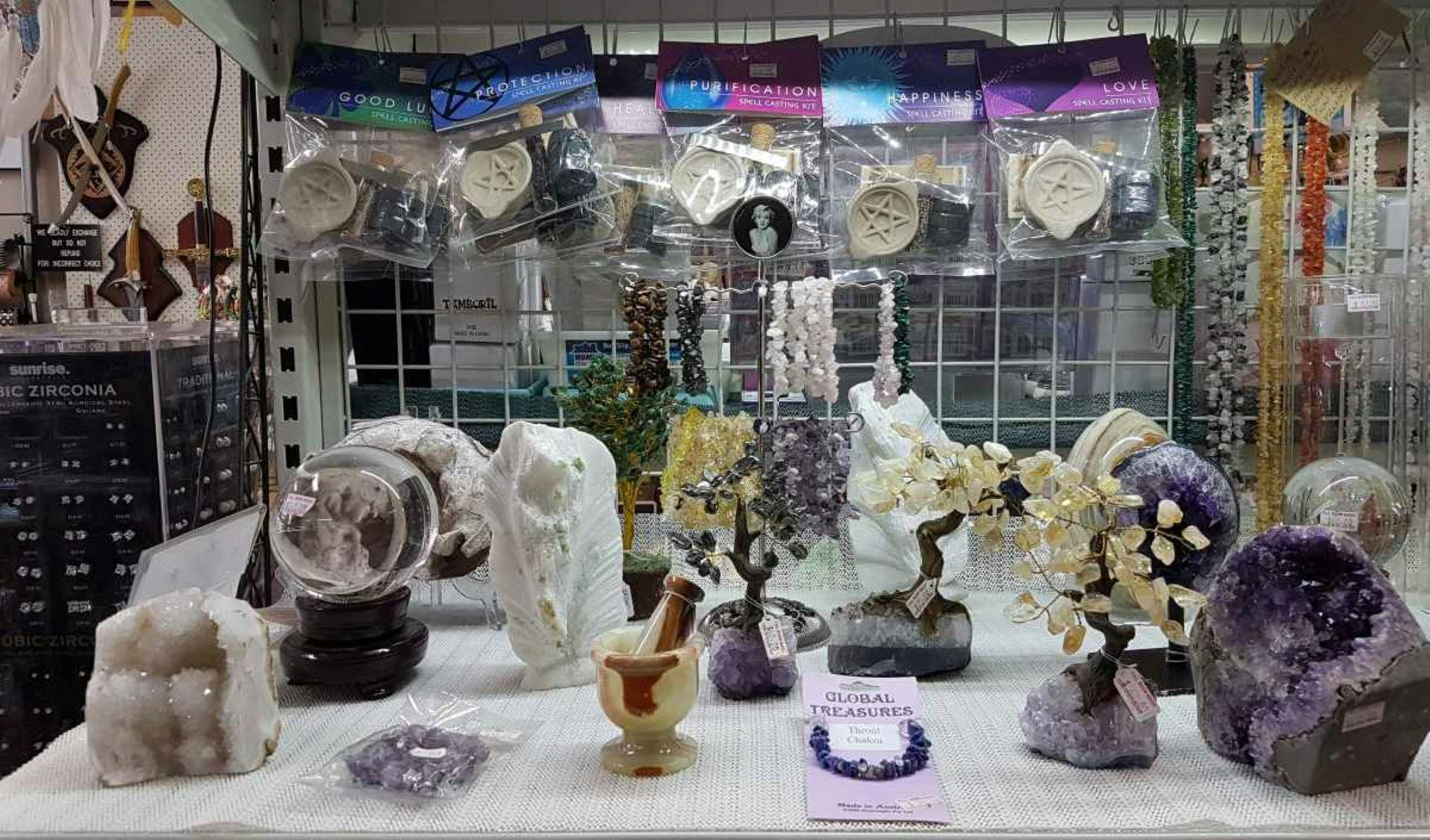 Table full of crystals of many types and spell casting kits.