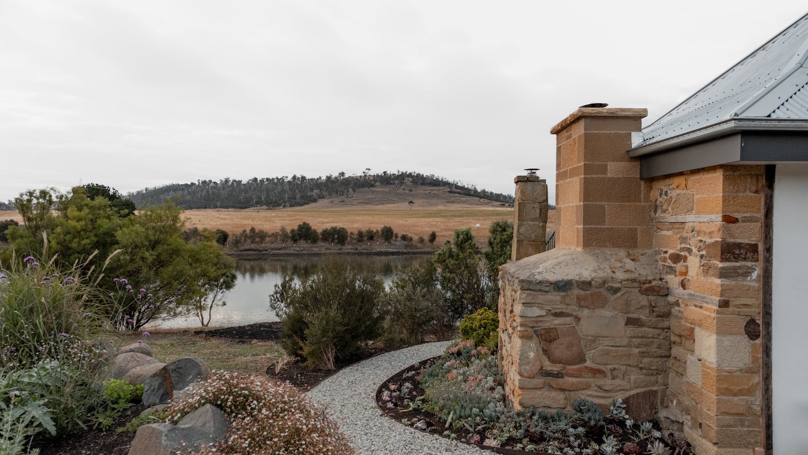 Landscaped gardens bridge the space between sandstone chimneys and the Carlton river