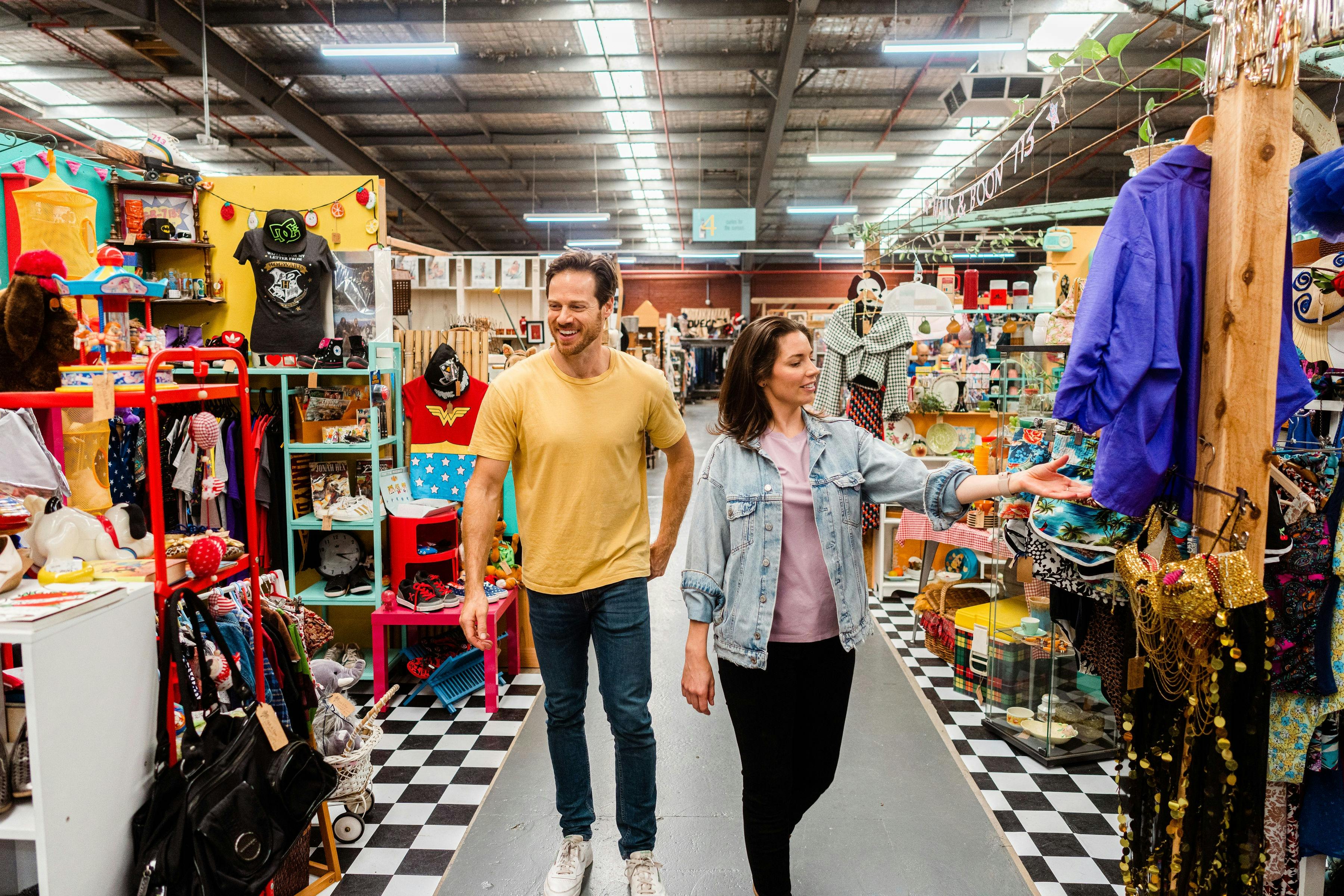 Man and woman browsing through aisles looking at vintage clothes and collectables