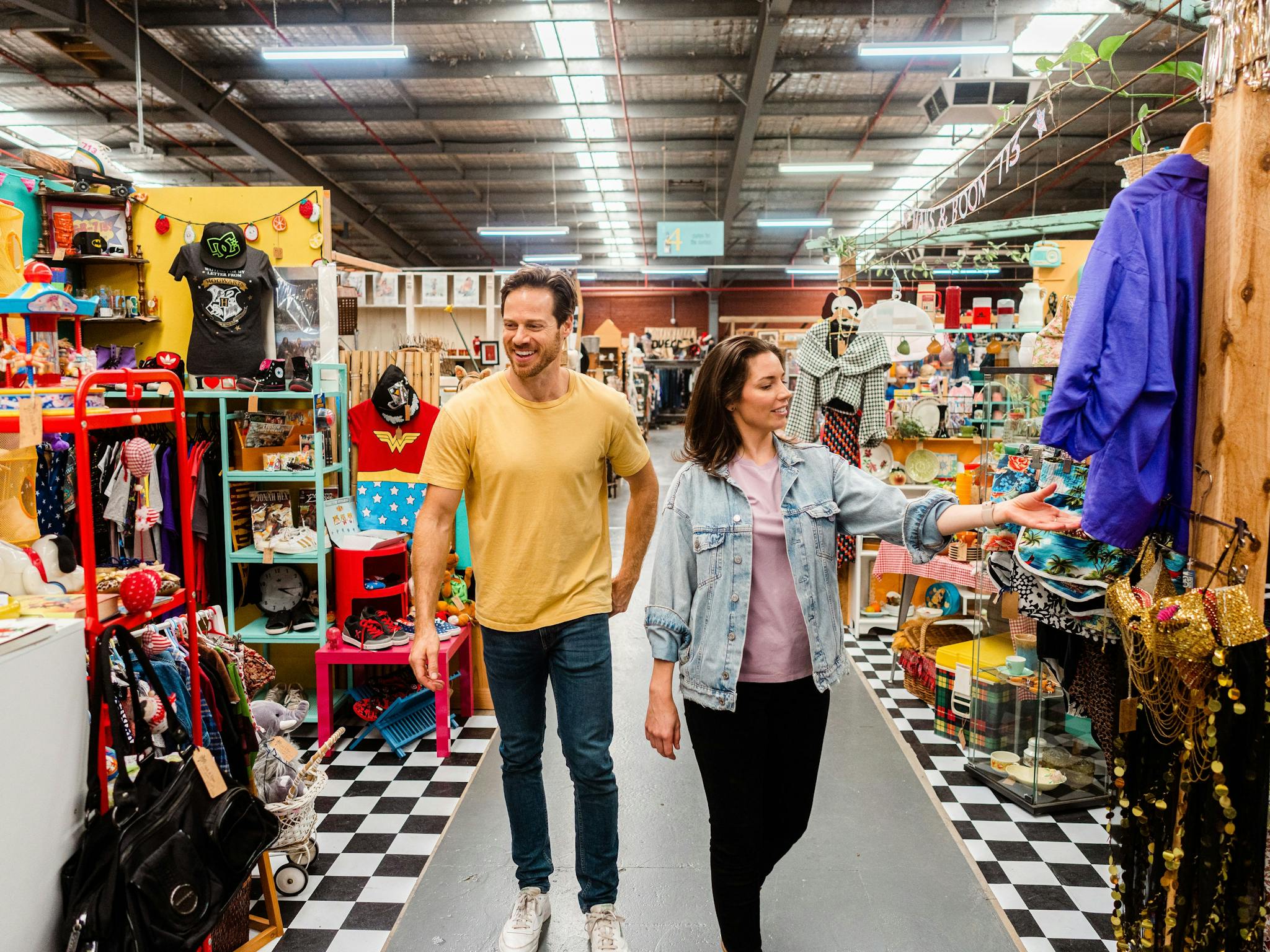 Man and woman browsing through aisles looking at vintage clothes and collectables