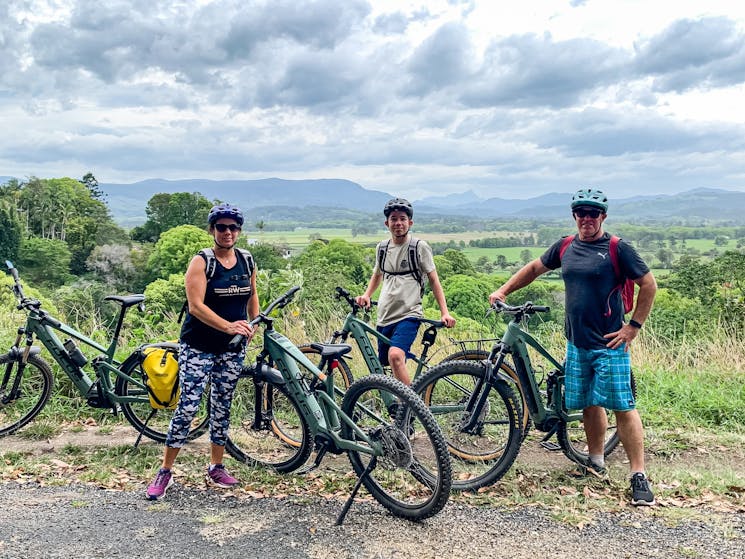parents and son standing by bikes overlooking countryside around mullumbimby