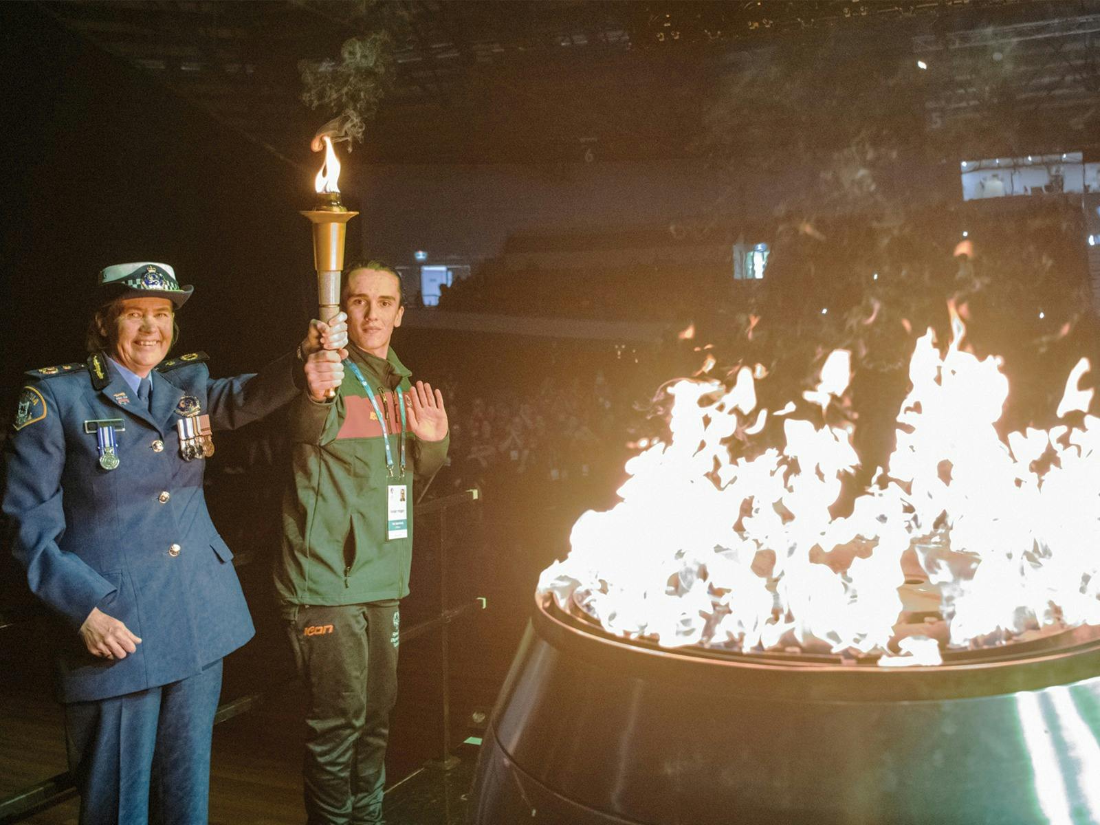 Two people hold the Special Olympics Torch above their head after lighting the cauldron