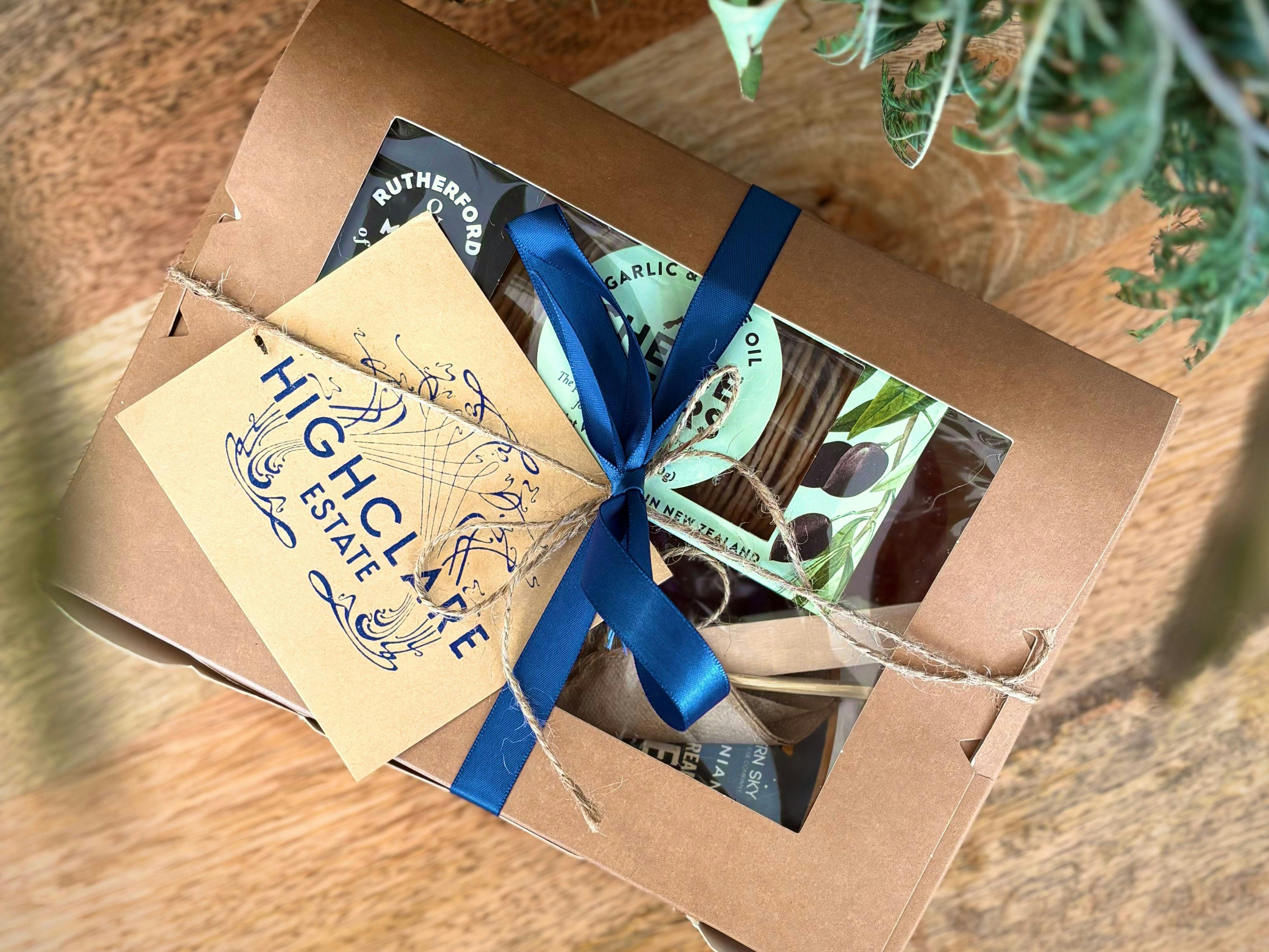Recycled paper box, window showing platter items contained within, blue ribbon and name tag
